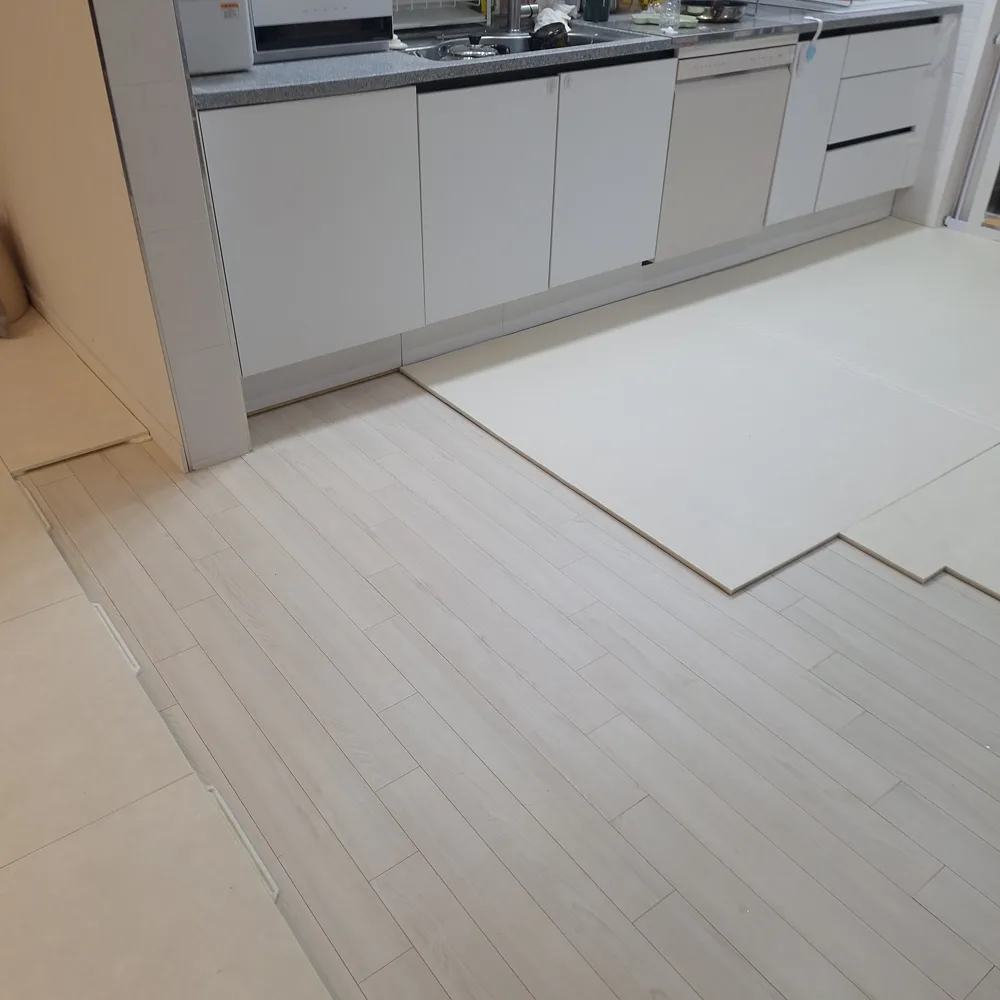 아일랜드식탁 자르기 리폼 중, 하부장이 빠진 자리에 밝은 판재가 깔려 있는 주방 바닥